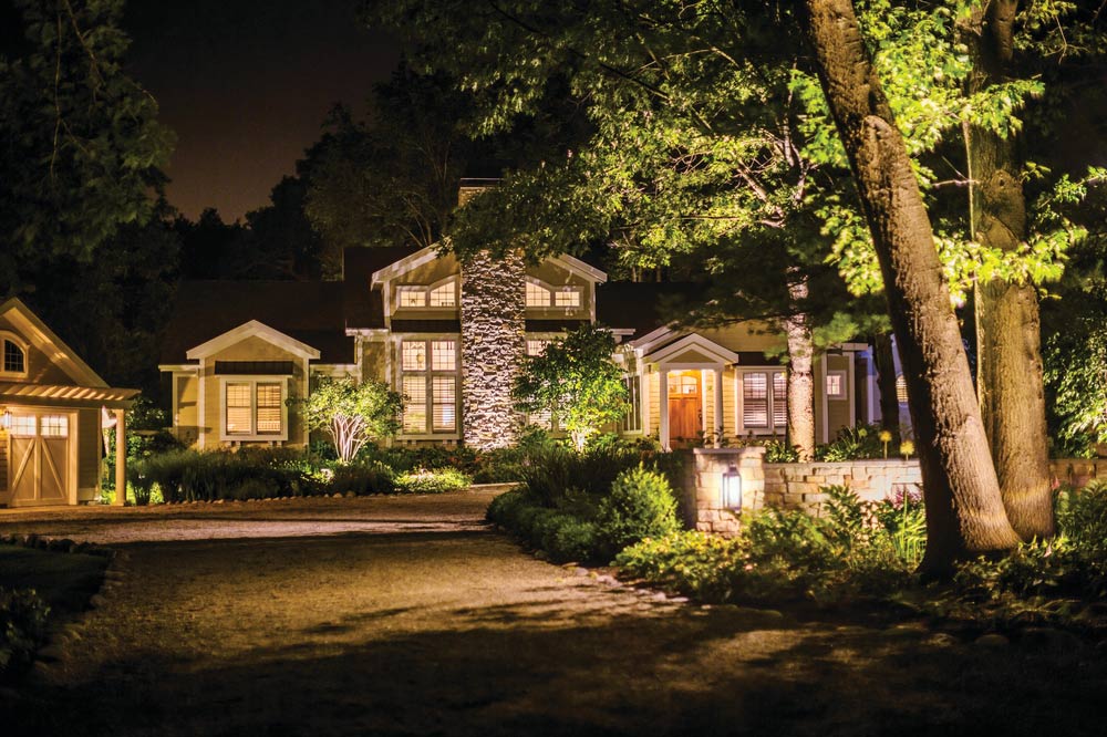 house with landscape lighting along driveway to home